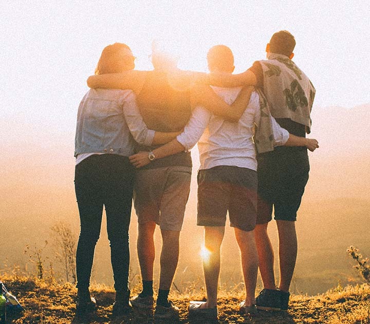 Four people with arms around each other while on a hike